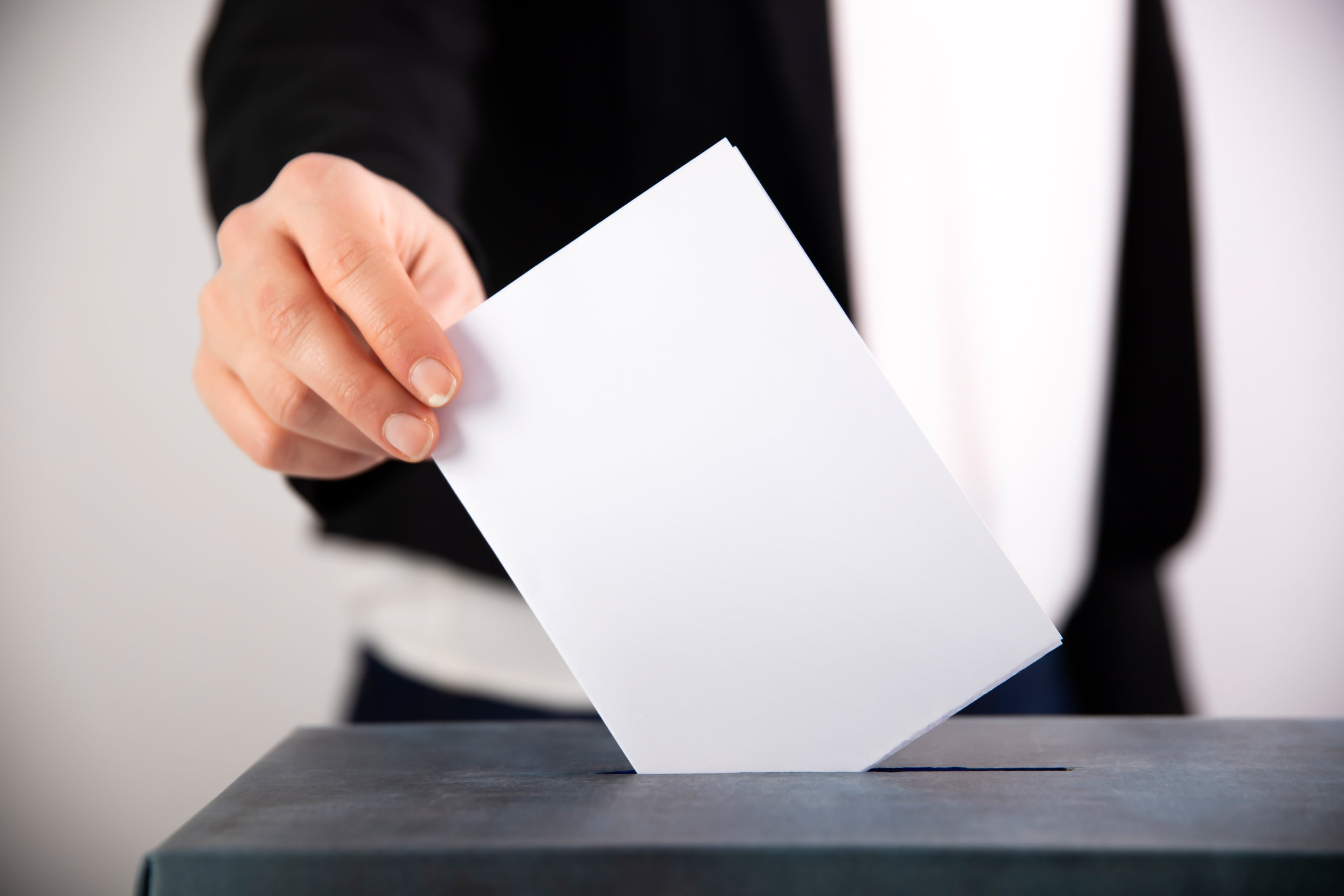 Person wirft Wahlschein in Wahlurne